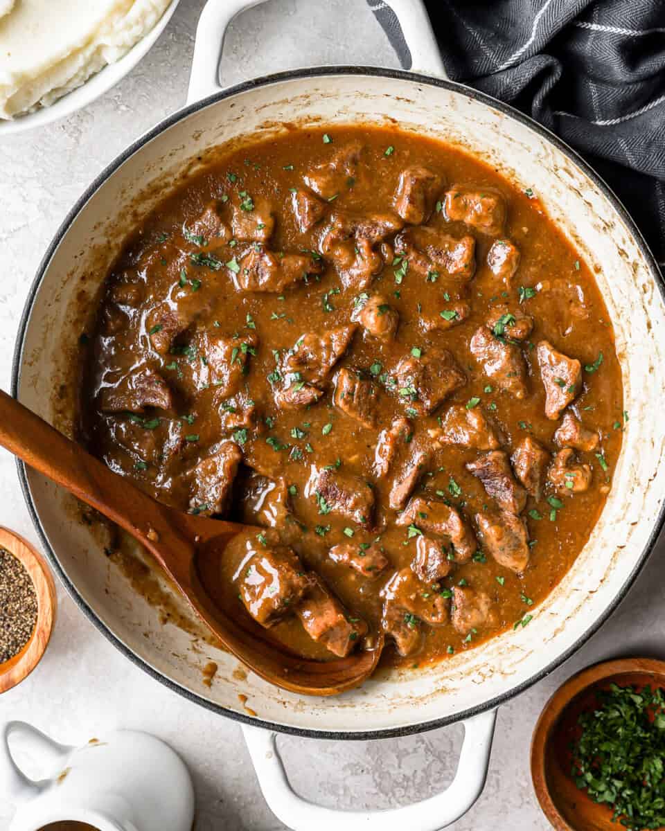 Overhead view of beef tips and gravy cooking in a pot.