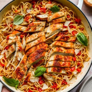 A pot of bruschetta chicken pasta with angel hair pasta, tomatoes, basil, and sliced chicken breasts.