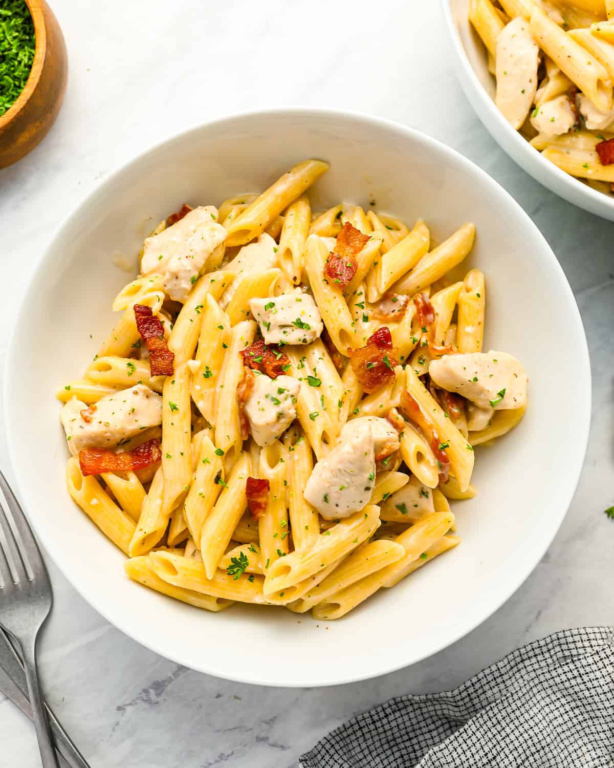 A serving of creamy chicken bacon ranch pasta in a white bowl.
