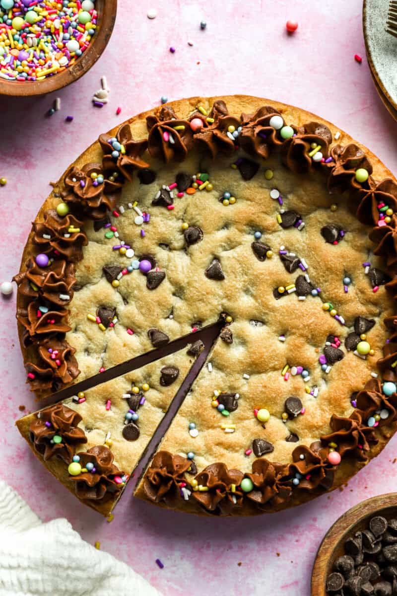 Homemade chocolate chip cookie cake with a triangular slice cut out.