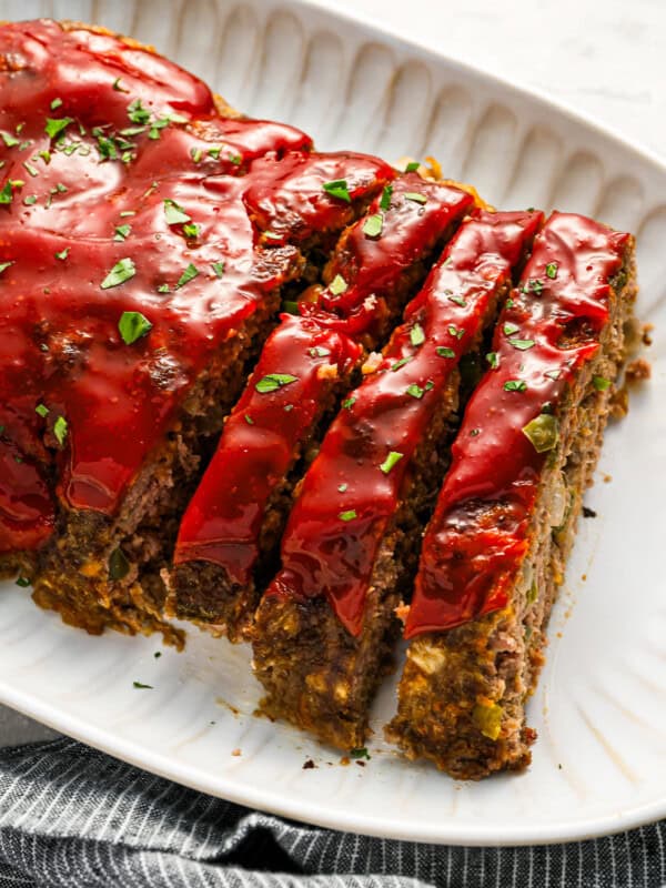 partially sliced cracker barrel meatloaf on a white serving platter.