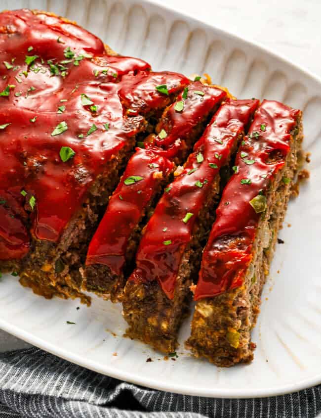 partially sliced cracker barrel meatloaf on a white serving platter.