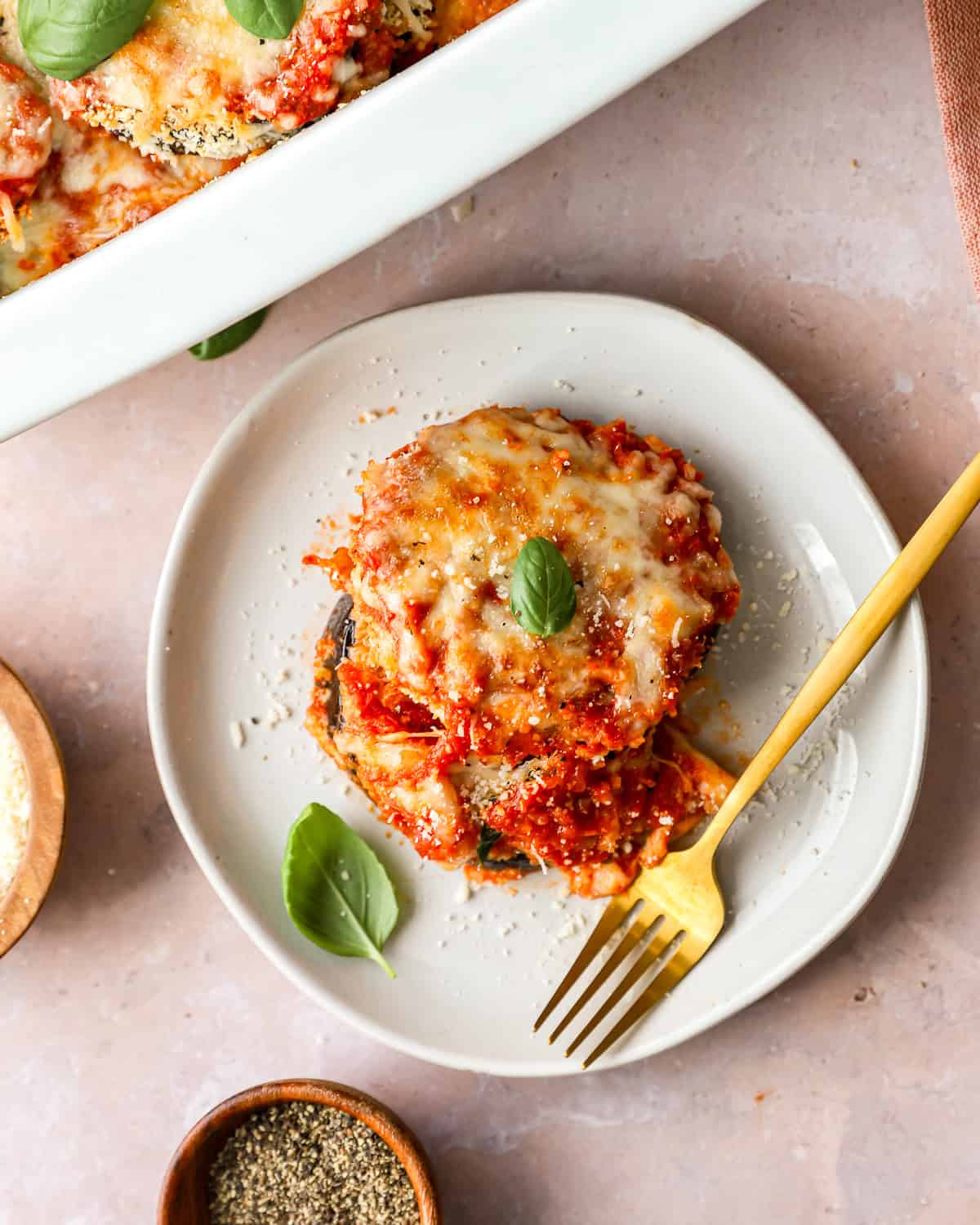 overhead view of a serving of eggplant parmesan on a white plate with a fork.