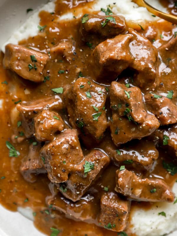 Beef tips and gravy in a bowl of mashed potatoes.