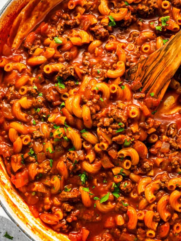 Beefaroni in a pot with a wooden spoon.