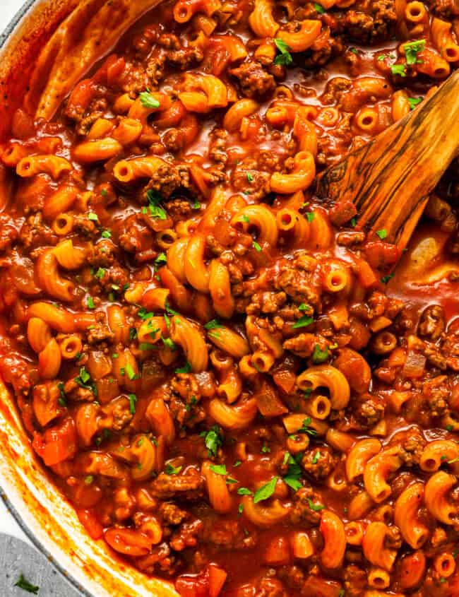 Beefaroni in a pot with a wooden spoon.