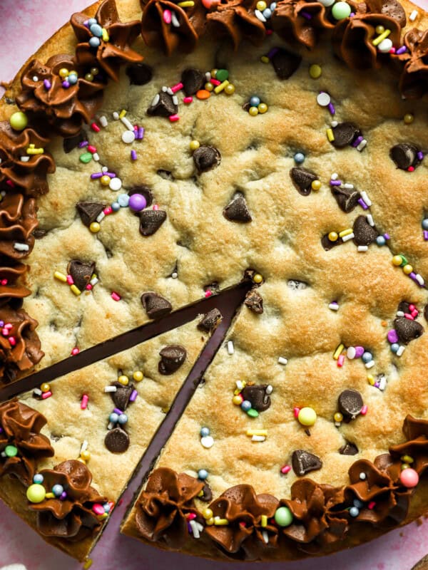 Homemade chocolate chip cookie cake with a triangular slice cut out.