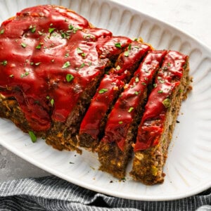 partially sliced cracker barrel meatloaf on a white serving platter.