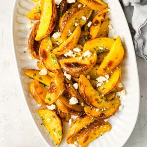 overhead view of greek potatoes topped with feta on a serving platter.