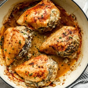 mushroom stuffed chicken breasts in a pan.