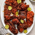 overhead view of nashville hot chicken on a white serving platter with pickles.