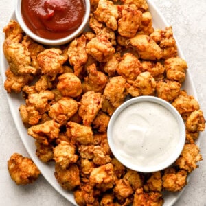 overhead view of popcorn chicken on a serving platter with mayo and ketchup.