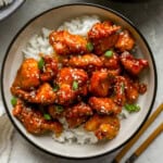 overhead view of sesame chicken over white rice in a bowl.