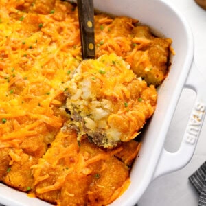 a serving of tater tot breakfast casserole on a spatula resting on the casserole.