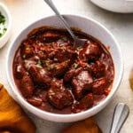 a serving of texas chili in a white bowl with a spoon.