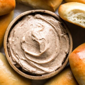 overhead view of texas roadhouse honey cinnamon butter in a bowl surrounded by rolls.