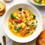 overhead view of a serving of tuscan chicken soup in a white bowl.