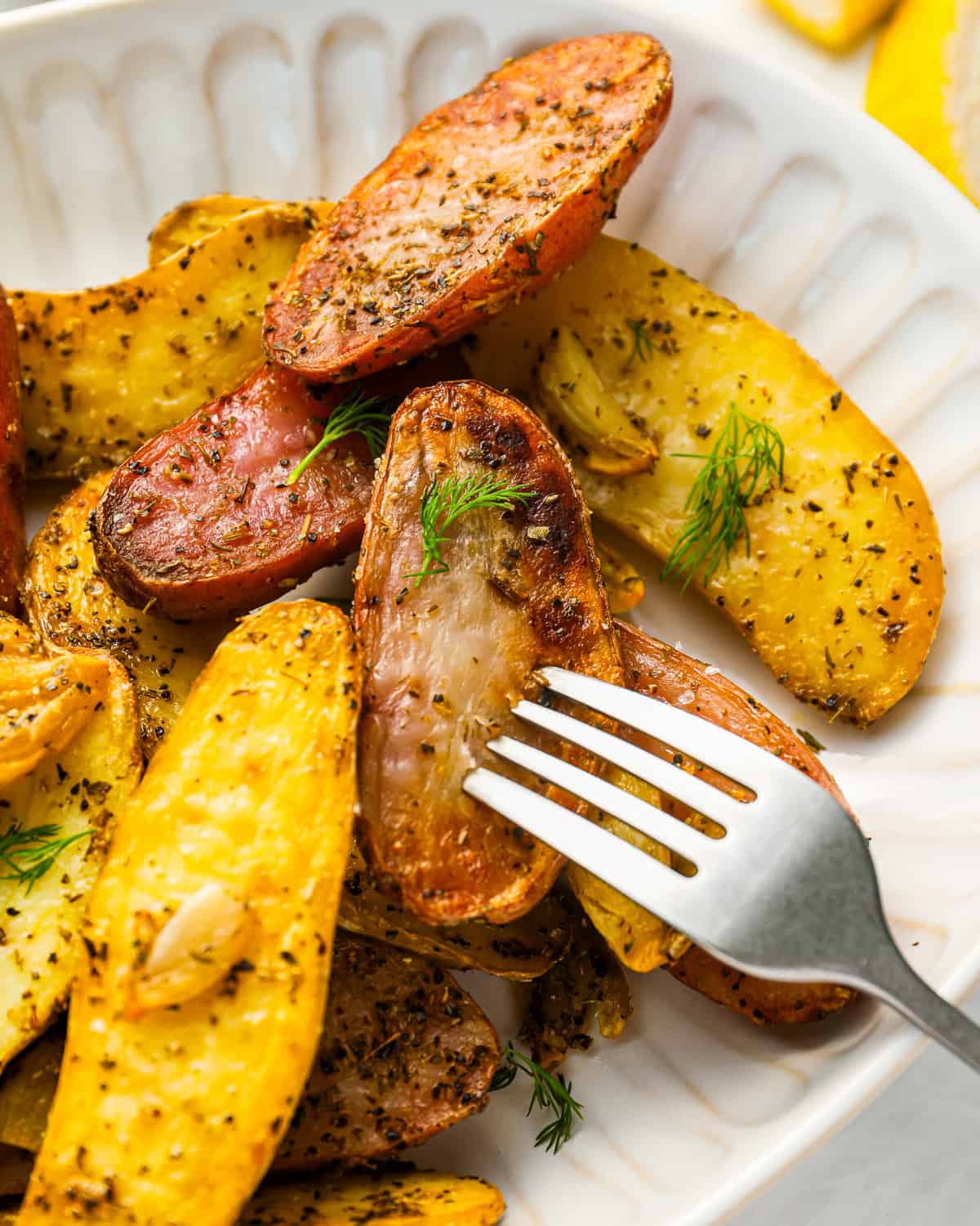 a fork stabbing a fingerling potato on a platter.