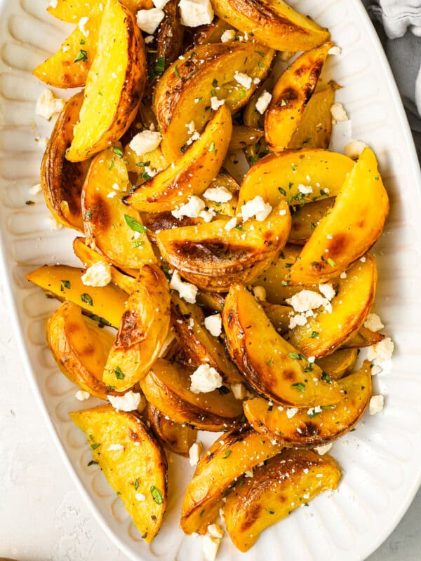 overhead view of greek potatoes topped with feta on a serving platter.