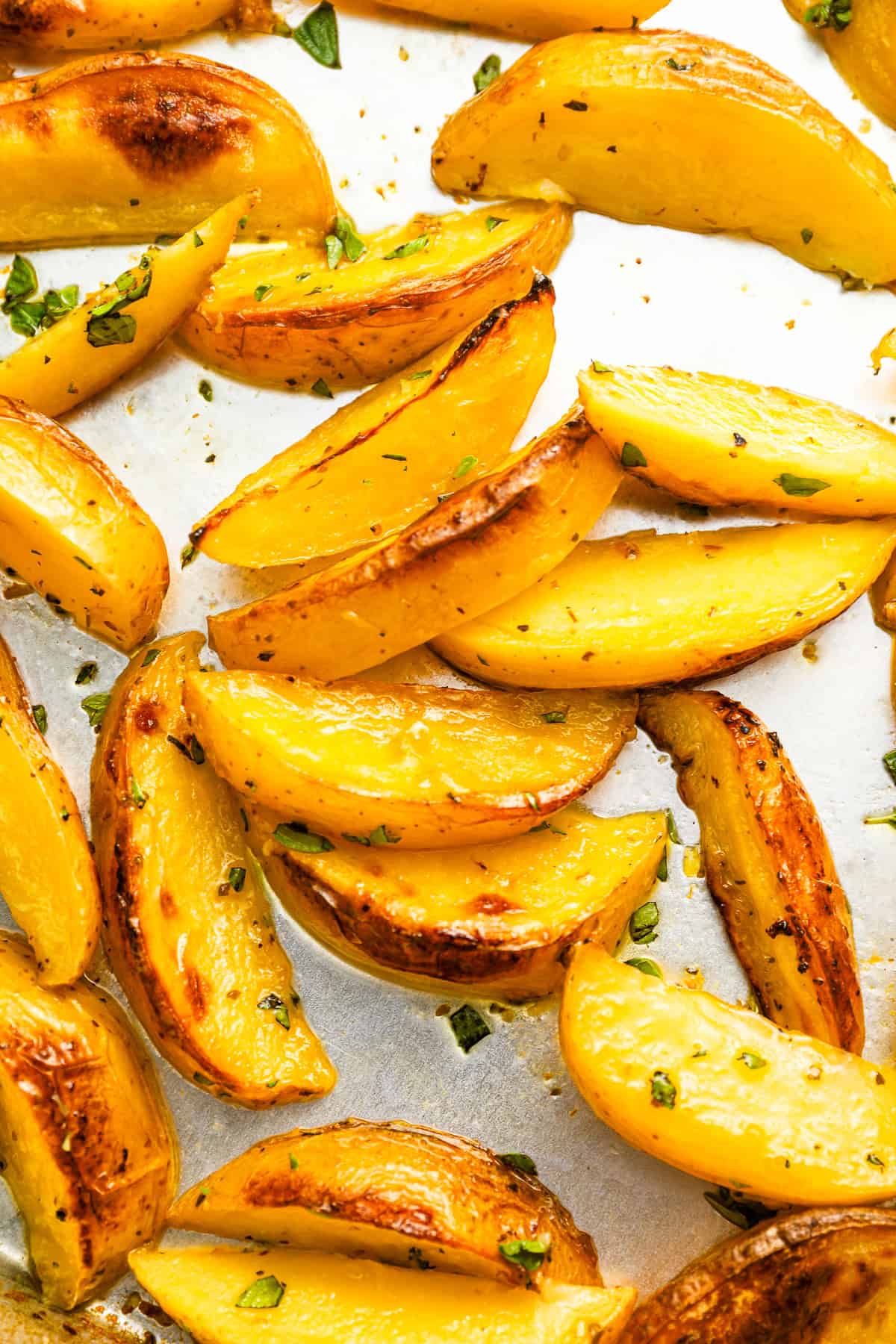 close up of greek potatoes on a baking sheet.