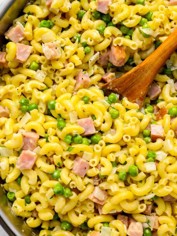 ham and pea pasta in a pot with a wooden spoon.