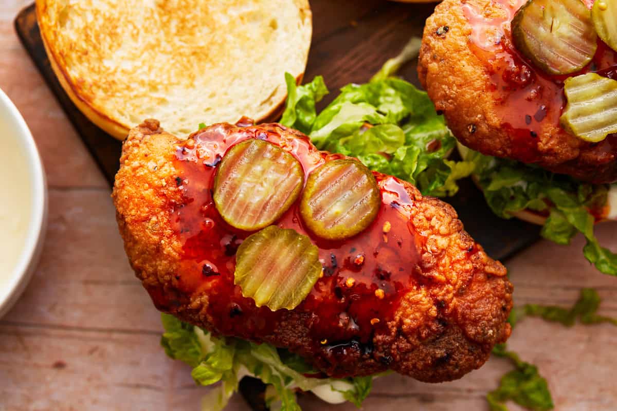 overhead view of an open hot honey chicken sandwich with pickles.