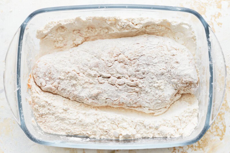 chicken coated in flour in a glass dish.