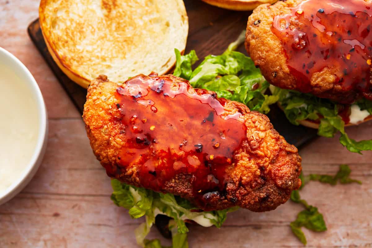 an open hot honey chicken sandwich on a cutting board.