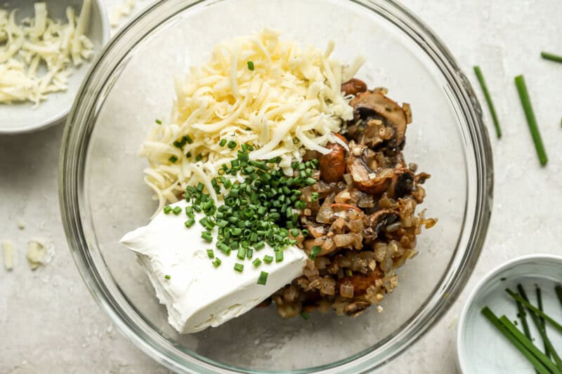 mushroom filling mixed with cheese, cream cheese, and chives in a glass bowl.