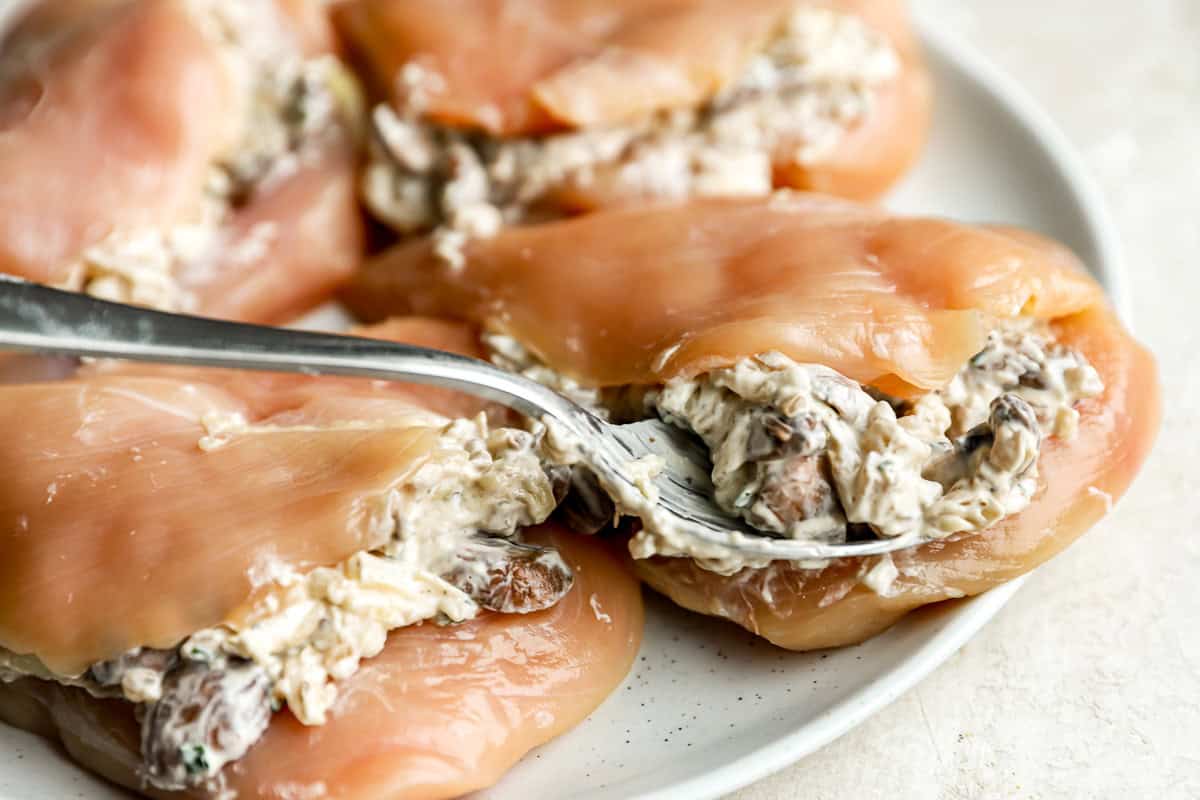 stuffing chicken breasts with mushroom filling.