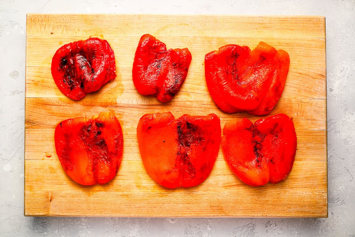 skinned roasted red peppers on a cutting board.