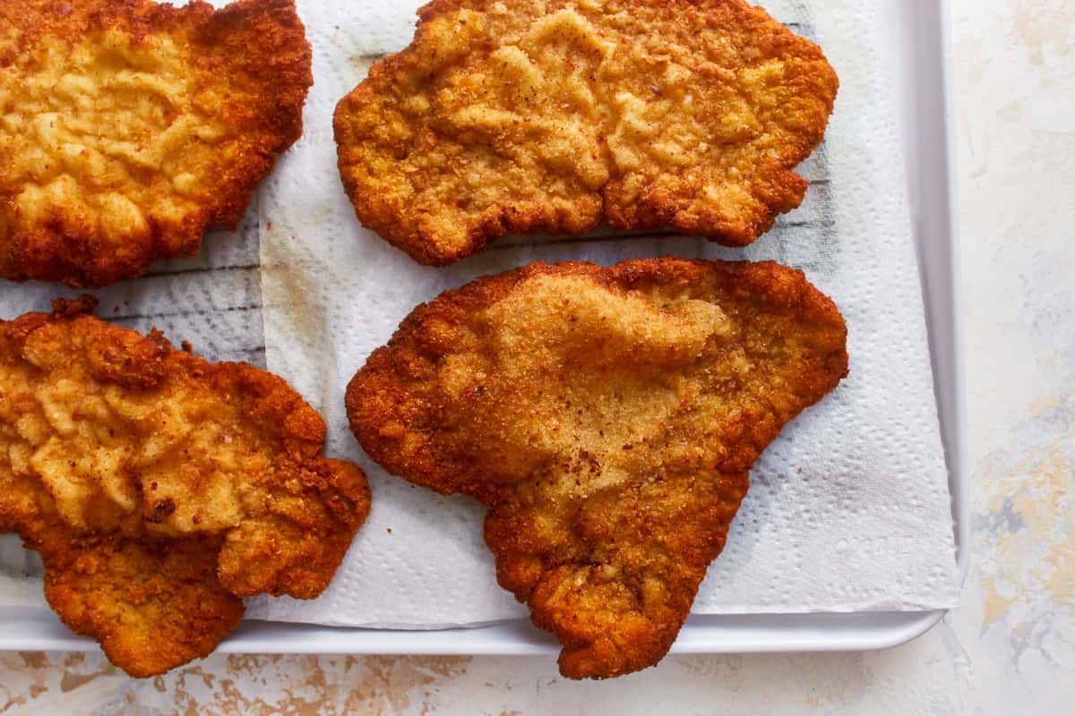 pork schnitzel cutlets draining on paper towels.