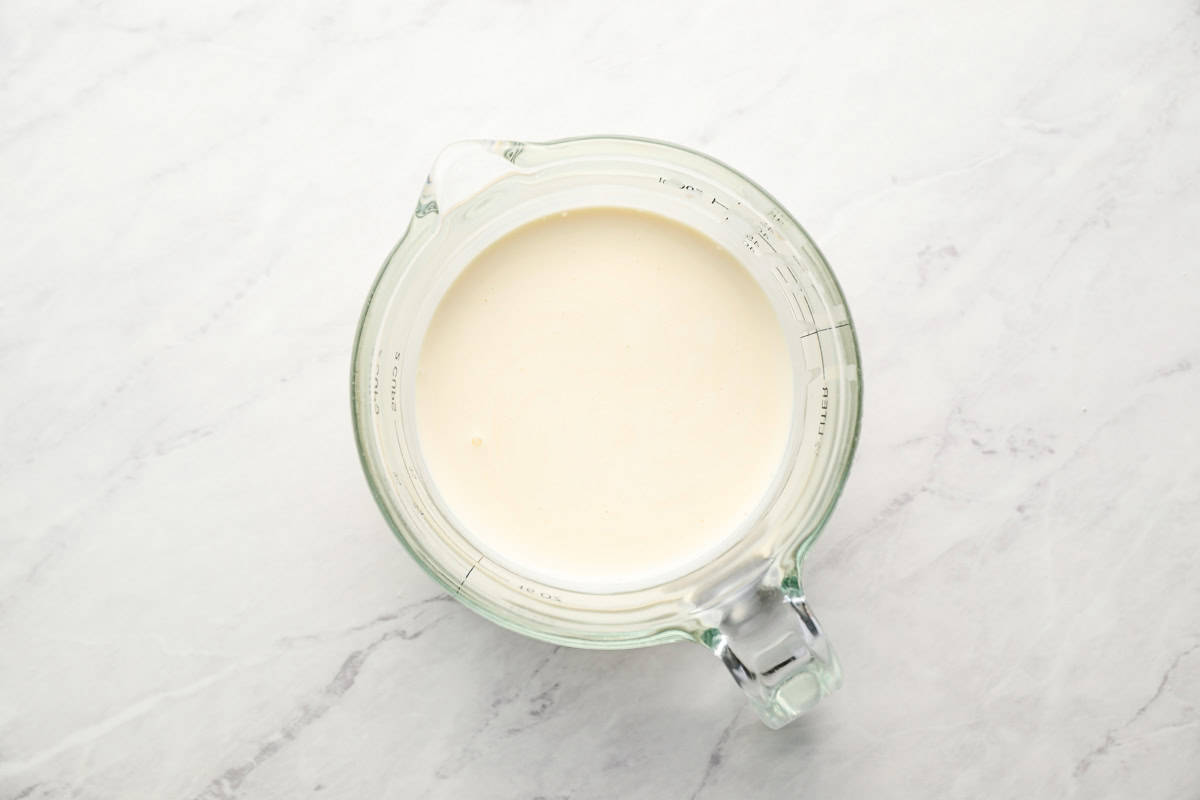 heavy cream in a glass measuring cup.