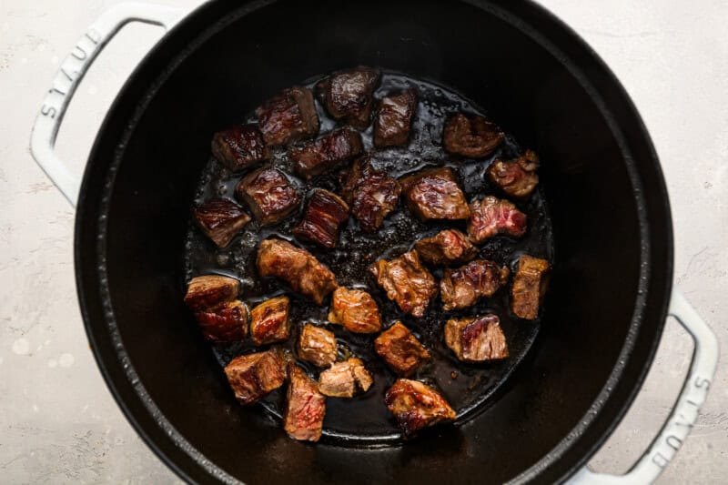 seared beef pieces in a dutch oven.