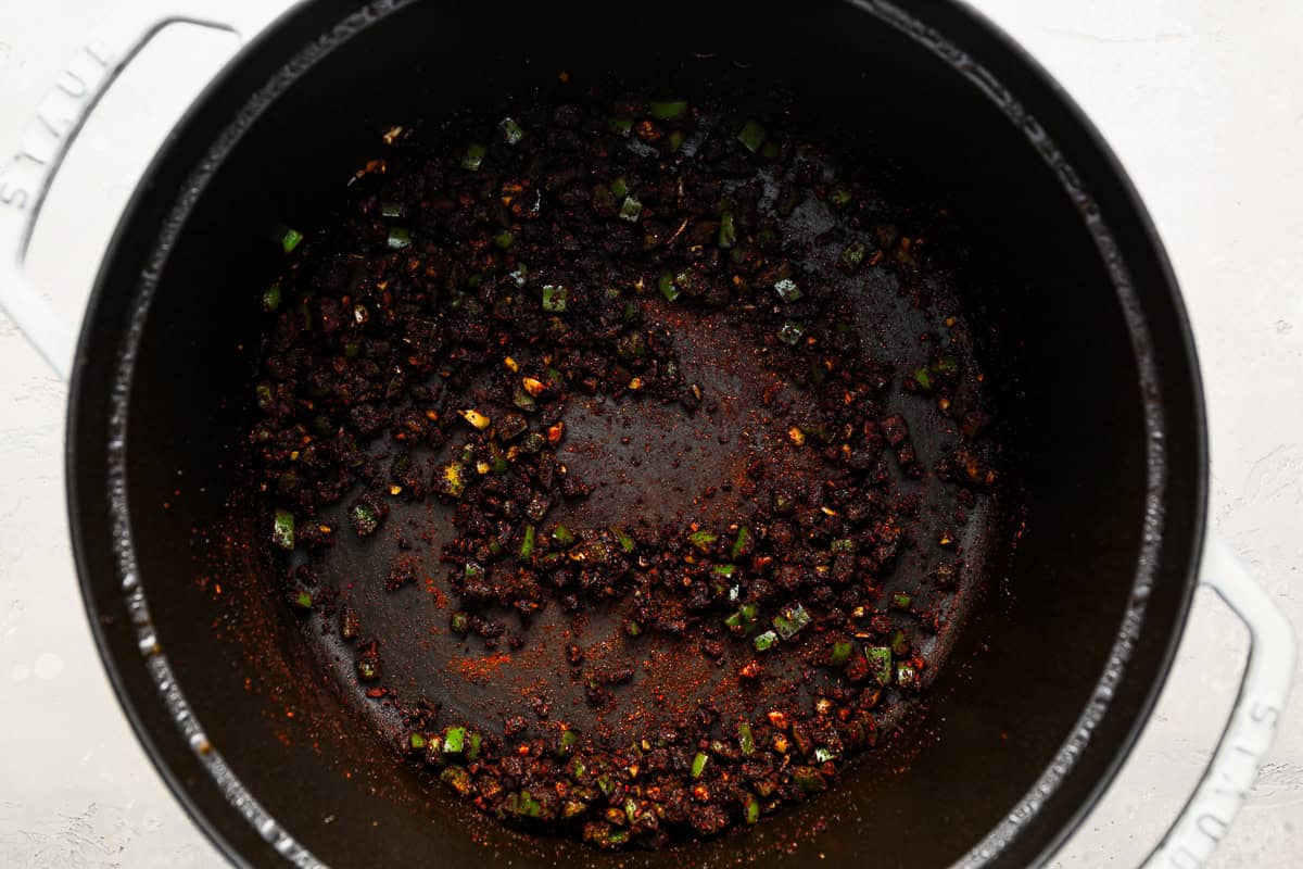 spices added to garlic and jalapeno in a dutch oven.