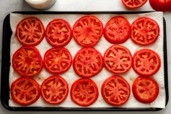 sliced tomatoes draining on paper towels.