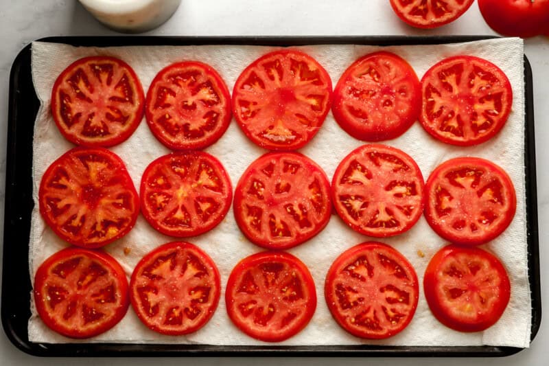 sliced tomatoes draining on paper towels.