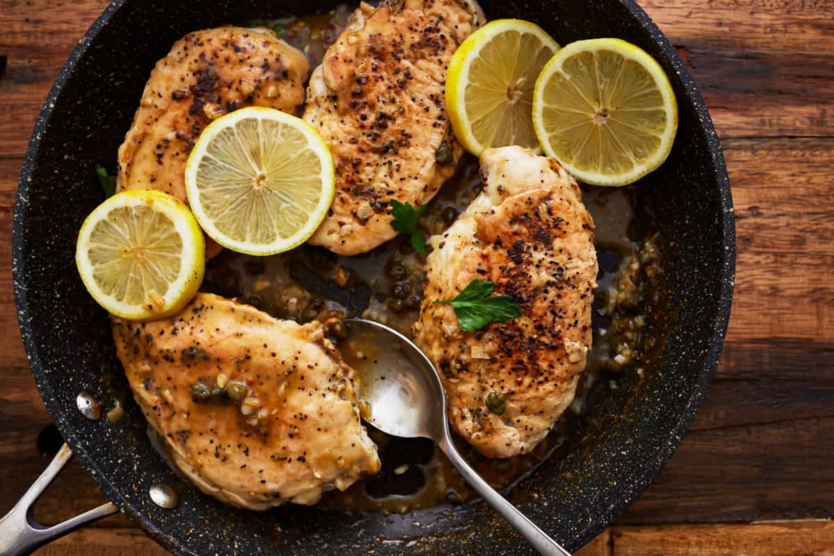 lemon pepper chicken in a pan with a spoon.