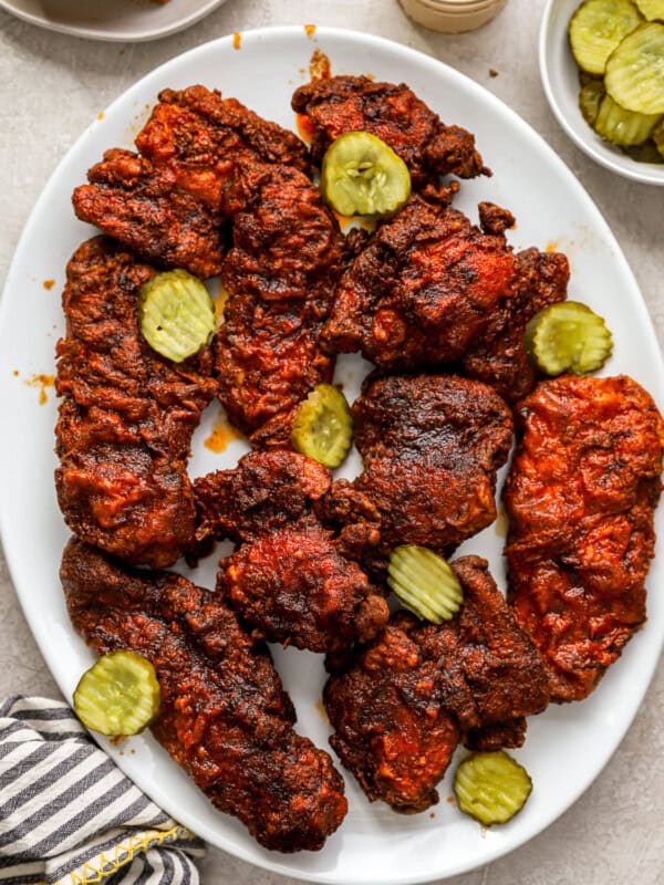 overhead view of nashville hot chicken on a white serving platter with pickles.