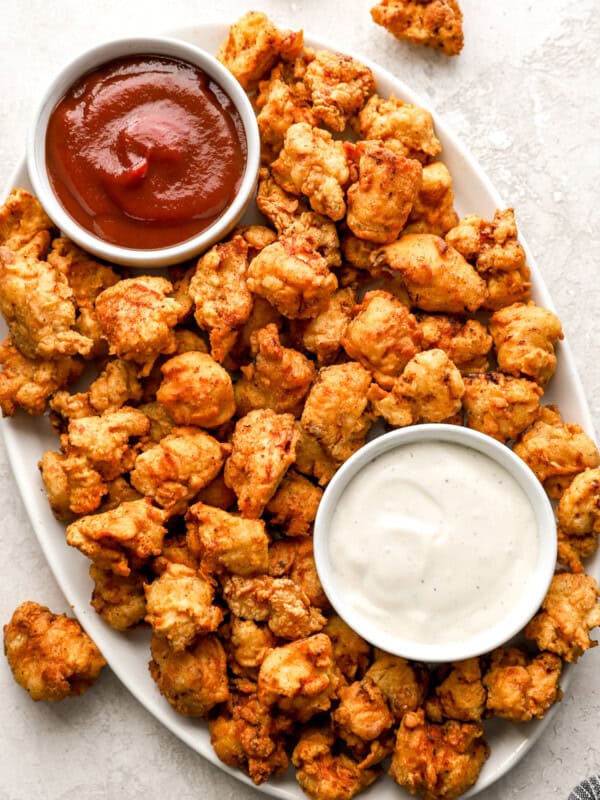 overhead view of popcorn chicken on a serving platter with mayo and ketchup.