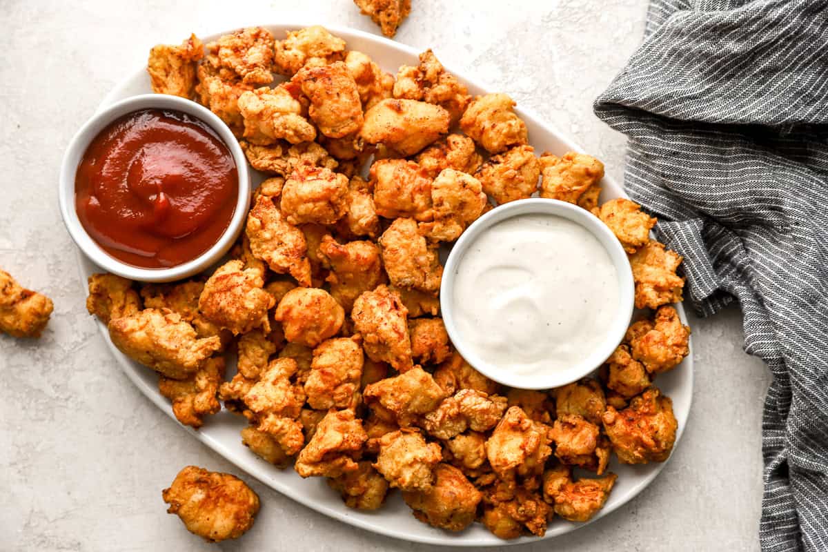 overhead view of popcorn chicken on a serving platter with mayo and ketchup.