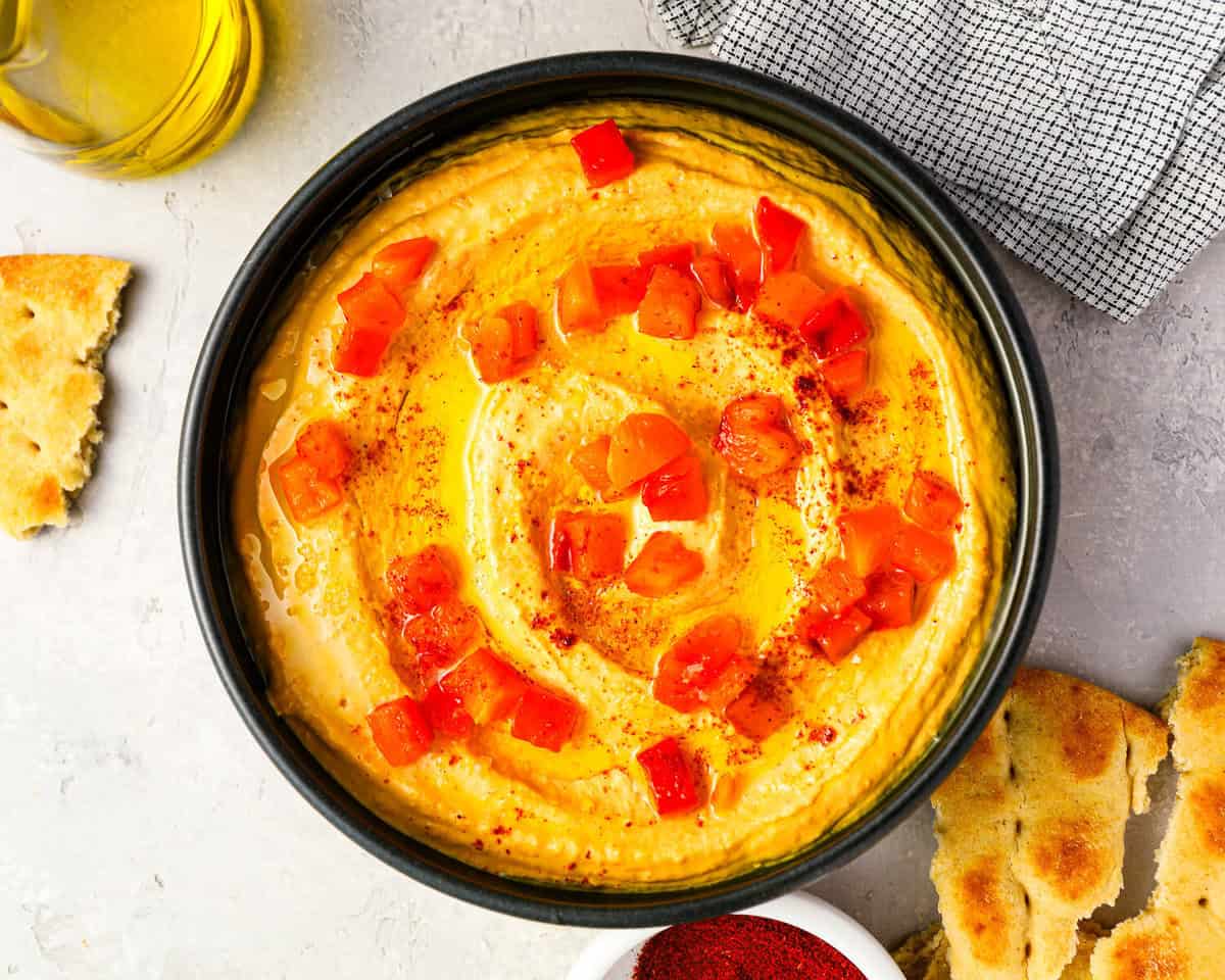 overhead view of roasted red pepper hummus with pepper pieces.