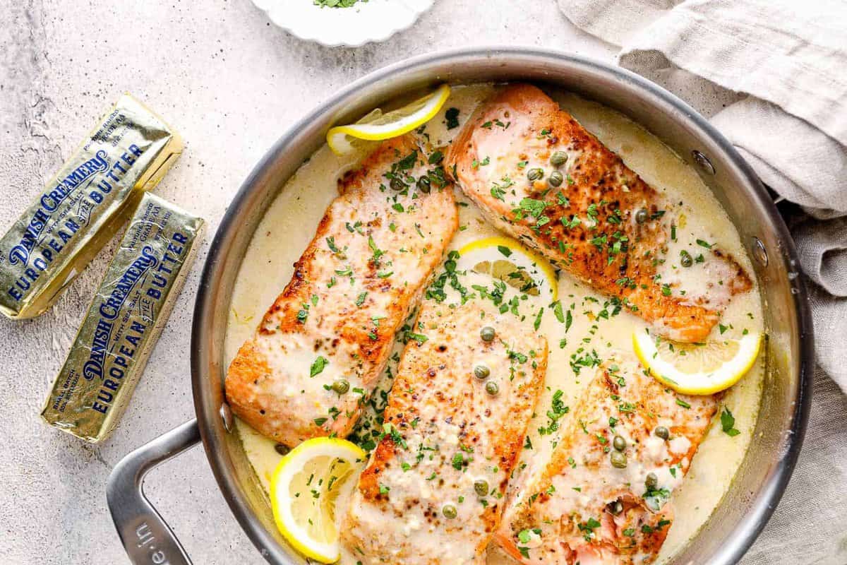 creamy salmon piccata in skillet with lemon slices