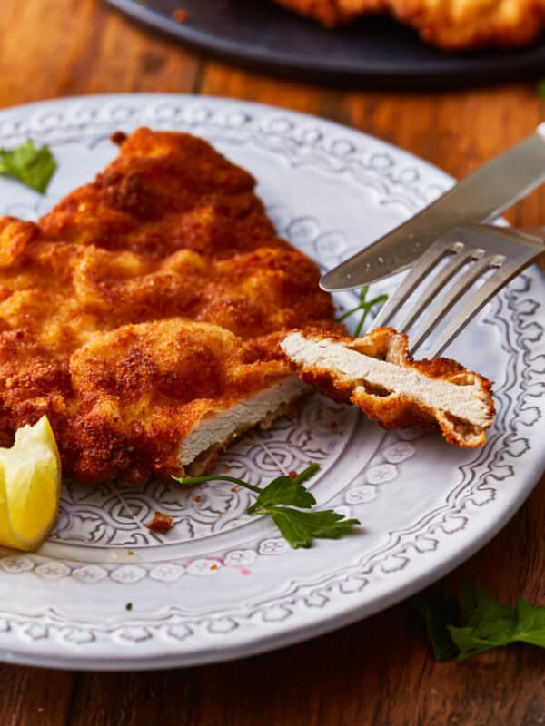 cut pork schnitzel on a plate with a fork and knife.