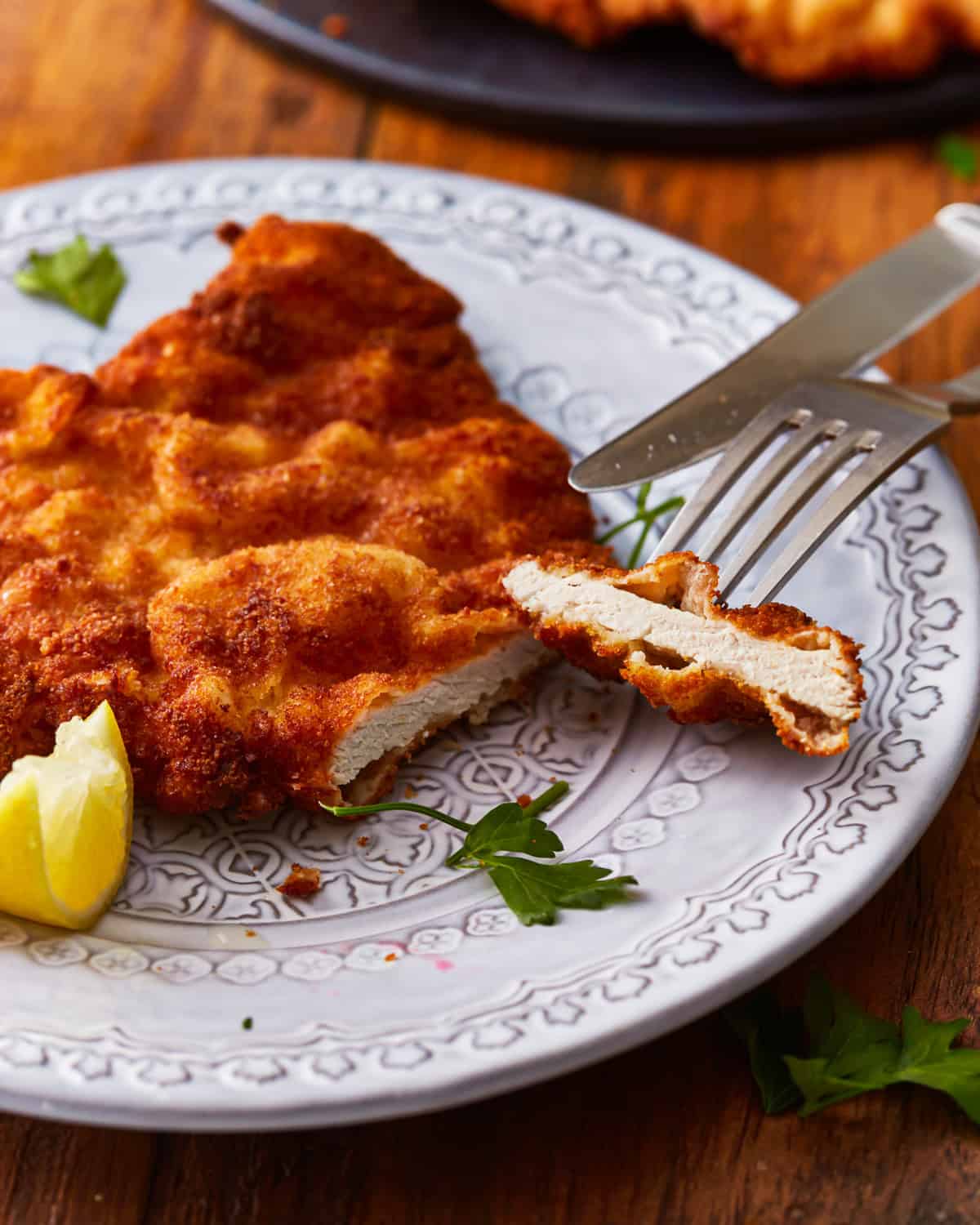 cut pork schnitzel on a plate with a fork and knife.