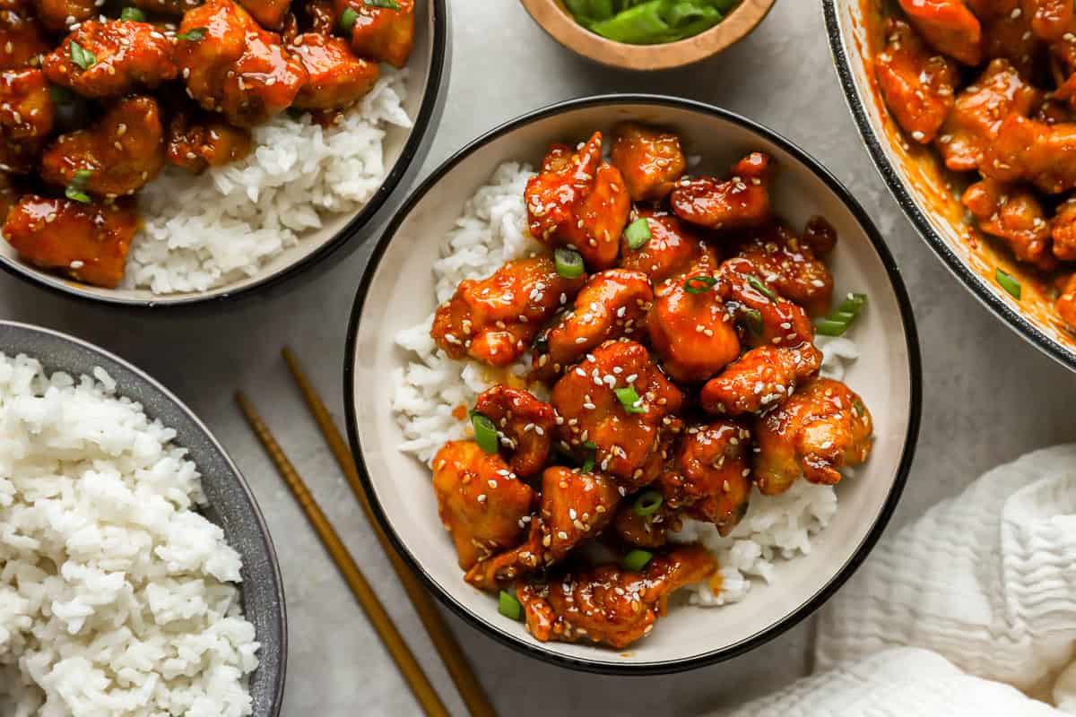 overhead view of sesame chicken over white rice in bowls.