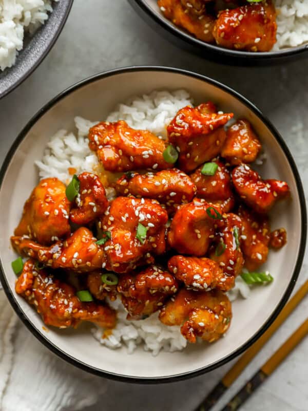 overhead view of sesame chicken over white rice in a bowl.