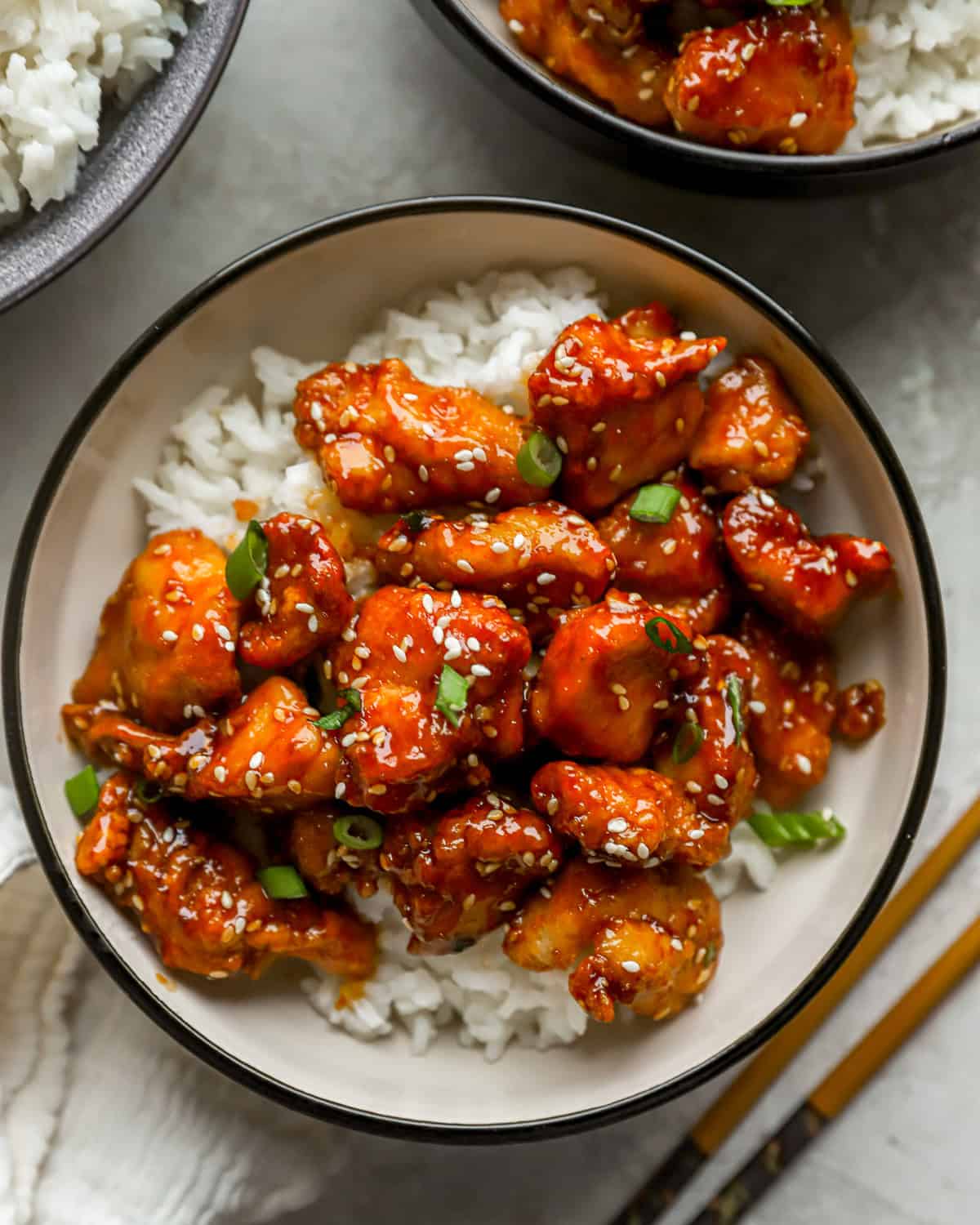 overhead view of sesame chicken over white rice in a bowl.