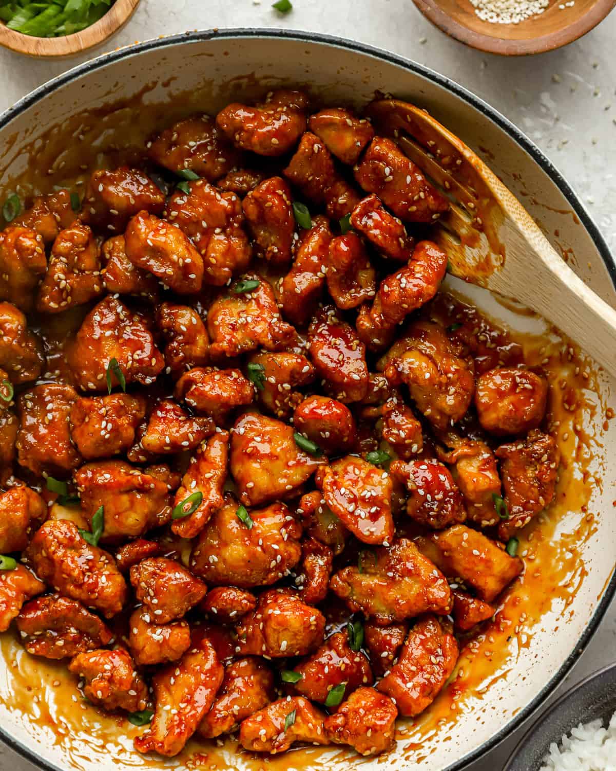 sesame chicken in a pot with a wooden spoon.