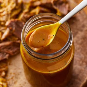 a spoon lifting carolina gold sauce from a mason jar.